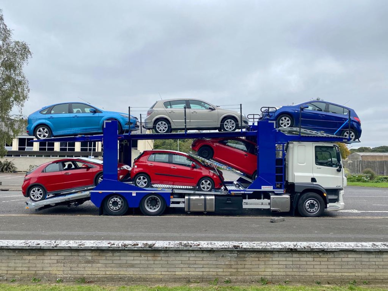 a blue transporter carrying vehicles to the auction