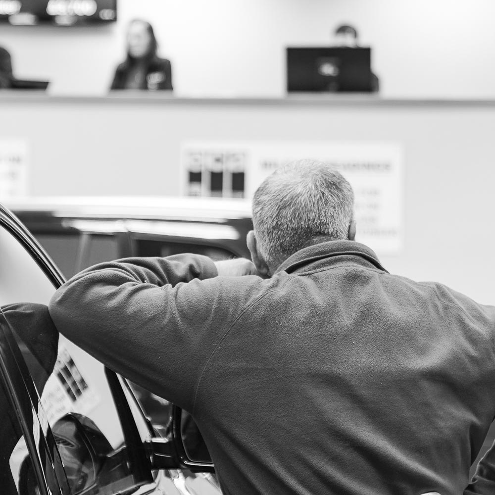 black and white photo man leaning on car from behind